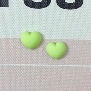 Gros plan de deux cœurs en résine mate vert clair pour la décoration d'ongles et bijoux