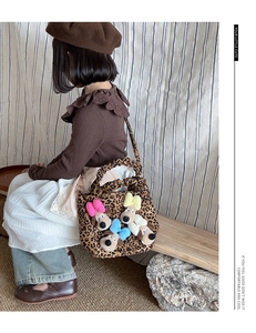 Girl's leopard print plush handbag with colorful dog charms shown in lifestyle use