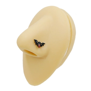 Detail of a black bat nose stud with red center on a silicone nose model for piercing
