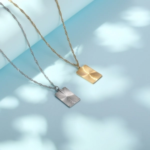 Minimalist gold and silver stainless steel rectangle pendant necklaces on blue background