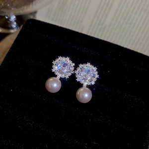 Macro view of flower zircon stud earrings with elegant pinkish-purple pearls