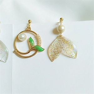 Detail of asymmetric mermaid earrings with gold leaf, pearls and sparkly whale tail charm