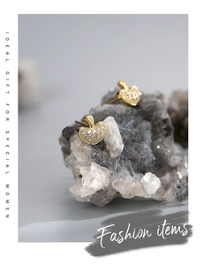 Macro shot of gold-plated apple stud earrings with pavé zircons on a natural stone base