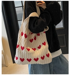 Detalle del tejido de punto del bolso bandolera beige con corazones rojos de ganchillo