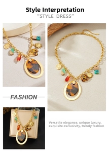 Macro detail of chunky gold necklace with amber resin oval pendant and sun charm
