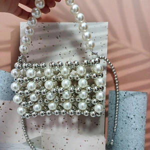 Detail of hand-woven beaded bag with white pearls and silver metallic beads