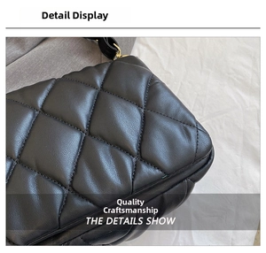 Detailed close-up of black quilted crossbody bag with diamond pattern and gold hardware