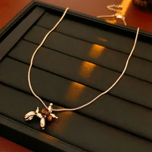 Gold-plated balloon dog pendant necklace with tiger eye stones on black tray