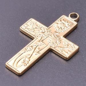 Detailed macro view of a gold-plated stainless steel cross pendant with floral engraving