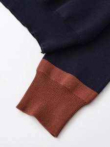 Detail of navy knit fabric and brick red ribbed cuff with fine stitching texture