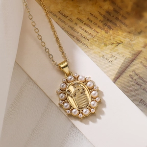 Gold plated copper necklace with pearl inlaid Virgin Mary medallion pendant on book page