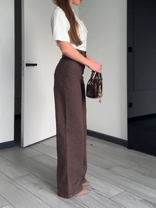 Women's high waist brown wide-leg denim jeans shown from a side profile on a model
