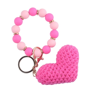 Close-up of pink crochet heart pendant with beaded wristlet keychain on white background
