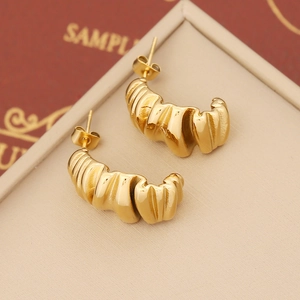 Macro detail of gold-toned geometric croissant stud earrings in a jewelry gift box