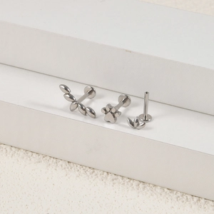 Details der 16G Edelstahl Labret-Stecker mit Blatt-, Pfoten- und Blumendesign auf weißem Sockel