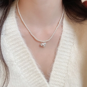Close-up of pearl necklace with a colorful enamel rocking horse pendant on a model