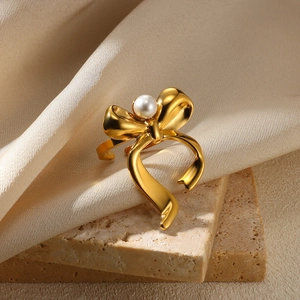 Macro shot of gold bow ring with pearl centerpiece on elegant textured background