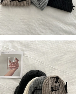 Detail view of knitted beanie hats with ribbon bows on a textured grid tablecloth