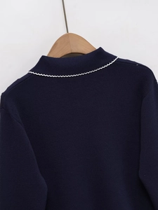 Detailed view of navy blue knit top featuring contrast white scalloped trim collar