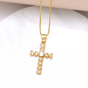 Gold cross pendant necklace with sparkling white cubic zirconia on marble surface