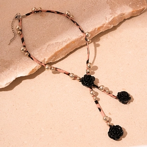 Détail d'un collier ras du cou en cuir léopard avec trois roses noires et perles