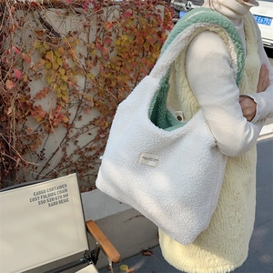 Close-up of fluffy beige reversible fleece tote bag with green lining in outdoor setting