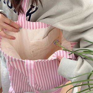 Detail of internal zipper pocket and canvas lining in striped tote bag for daily storage