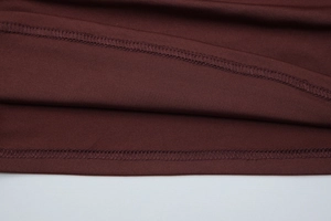 Detailed close-up of double-needle stitching on dark brown elastic knit fabric top