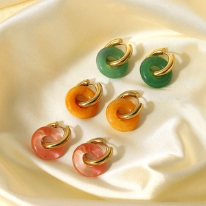 Three-pair gold hoop earring set with green, orange, and pink stone charms on silk background