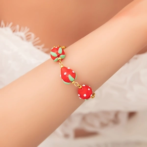 Handmade stainless steel bracelet with three red glass strawberry pendants on a model's wrist