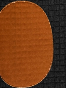 Detailed macro view of orange suede elbow patch stitched on charcoal grey plaid fabric