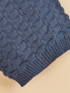 Macro shot of dark blue knit dog sweater showing dense checkered texture and ribbed cuffs