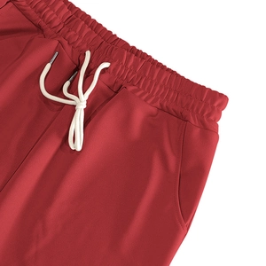 Détail du pantalon de sport rouge avec taille élastique, cordon en coton blanc et poches