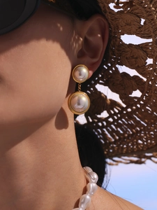 Detailed view of elegant double pearl drop earrings with iridescent luster on a model