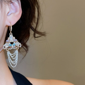 Close-up of bohemian gold earrings featuring colorful gemstones and multi-layer silver tassels