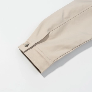 Detail of khaki jacket sleeve with smooth fabric texture and metal snap button closure