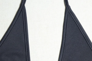 Detailed close-up of thin straps and textured black stretch fabric on a deep V-neck dress