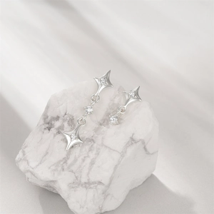 Detail of silver star earrings with round zircons on marble background