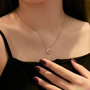 Detail of silver necklace with double-halo square yellow stone on a model collarbone
