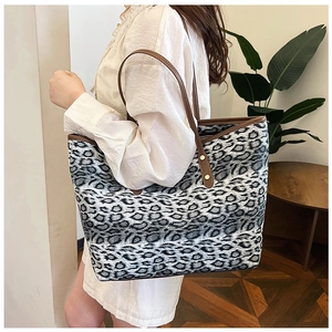 Gros plan détaillé du sac cabas léopard avec anses en cuir brun et rivets en métal