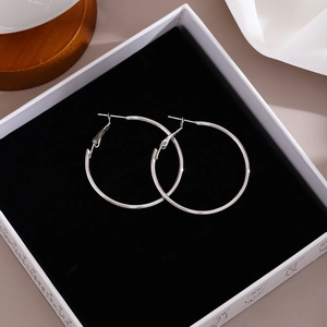 Detailed close-up of classic silver hoop earrings on elegant black velvet jewelry box