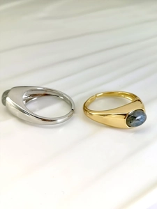 Detail view of gold and silver rings with oval labradorite stones on white background