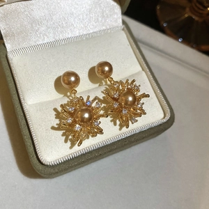 Dettaglio macro di orecchini a fiore in perla placcati oro 18K con zirconi scintillanti
