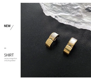 Detailed close-up of C-shaped titanium earrings with gold finish and shell inlay