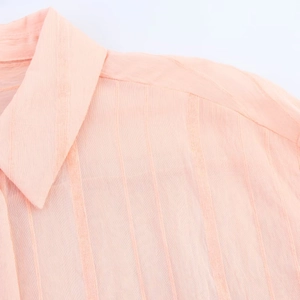 Detalle de camisa rosa con textura de rayas verticales y diseño de cuello alto moderno