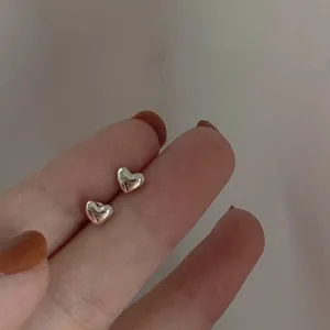 Close-up of polished S925 sterling silver heart-shaped stud earrings being held by hand