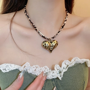 Close-up of heart-shaped leopard print pendant necklace on elegant woman neck