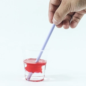 Silicone stir stick mixing red resin dye in clear cup for DIY epoxy craft work