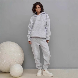 Detail of grey hooded tracksuit set featuring knitted cotton texture and minimal logo