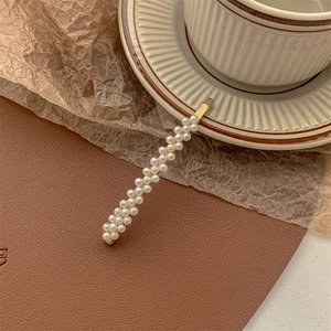 Close-up of gold pearl hair clip on leather mat and ceramic cup in vintage style